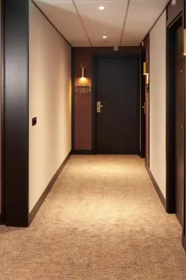 an empty hallway with a black door and a carpet at Golden Tulip Leiden Centre in Leiden