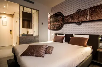 a bedroom with a large white bed with brown pillows at Golden Tulip Leiden Centre in Leiden