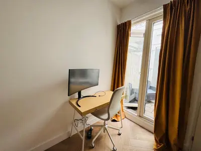 a desk with a computer in a room with a window at Sunshine Suites in Utrecht