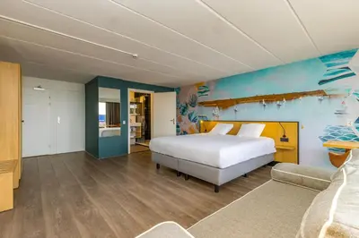 a bedroom with a bed and a blue wall at Fletcher Hotel Restaurant Loosdrecht-Amsterdam in Loosdrecht