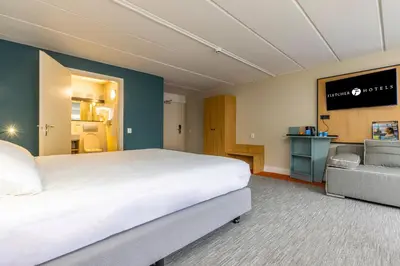 a hotel room with a large bed and a couch at Fletcher Hotel Restaurant Loosdrecht-Amsterdam in Loosdrecht