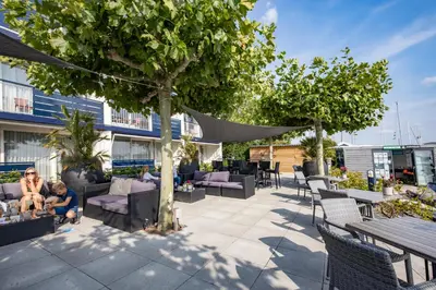 a patio with couches and tables and a tree at Fletcher Hotel Restaurant Loosdrecht-Amsterdam in Loosdrecht