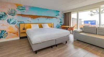 a bedroom with a large bed and a room with a couch at Fletcher Hotel Restaurant Loosdrecht-Amsterdam in Loosdrecht