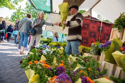 a man handing out flowers at a farmers market at Westerdok25 in Amsterdam