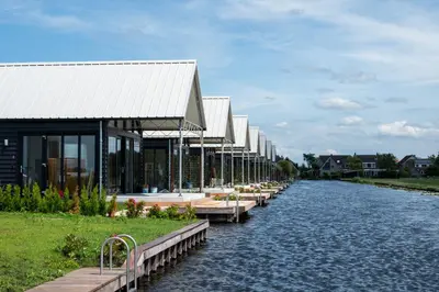 a row of buildings on the side of a river at 4 to 6 persons Tulpenacker waterfront in Roelofarendsveen