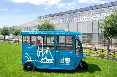 a blue van parked in the grass in front of a building at 4 to 6 persons Tulpenacker waterfront in Roelofarendsveen