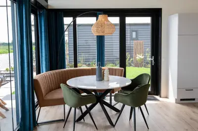 a dining room with a table and green chairs at 4 to 6 persons Tulpenacker waterfront in Roelofarendsveen