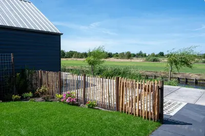 a wooden fence in front of a yard at 4 to 6 persons Tulpenacker waterfront in Roelofarendsveen