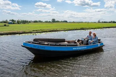 two people and a dog on a boat in the water at 4 to 6 persons Tulpenacker waterfront in Roelofarendsveen