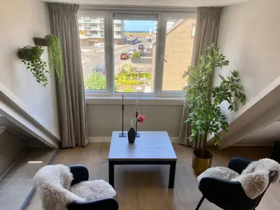 a living room with a table and chairs and a window at Glücklich am Meer Meerblick mit Wellnesszugang in Egmond aan Zee