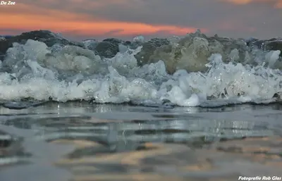 a foamy wave in the ocean at sunset at Glücklich am Meer Meerblick mit Wellnesszugang in Egmond aan Zee
