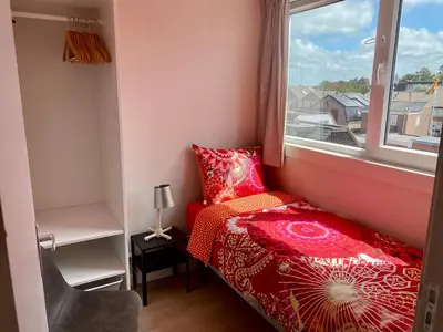 a small bedroom with a red bed and a window at Glücklich am Meer Meerblick mit Wellnesszugang in Egmond aan Zee