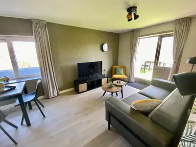 a living room with a couch and a table at Glücklich am Meer Meerblick mit Wellnesszugang in Egmond aan Zee
