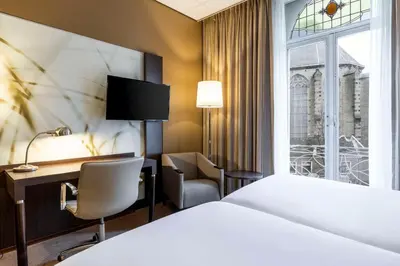 a hotel room with a bed and a desk and a window at NH Centre Utrecht Hotel in Utrecht