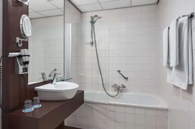 a bathroom with a tub and a sink and a shower at NH Centre Utrecht Hotel in Utrecht