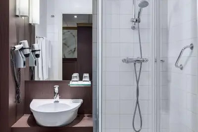 a bathroom with a shower with a sink and a shower at NH Centre Utrecht Hotel in Utrecht