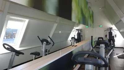 a gym with a row of exercise bikes on a wall at Hotel Theater Figi in Zeist