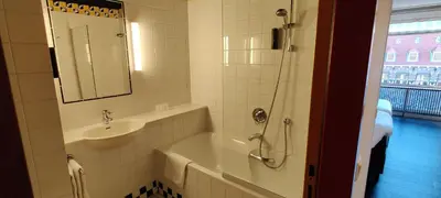 a bathroom with a tub and a sink and a mirror at Hotel Theater Figi in Zeist
