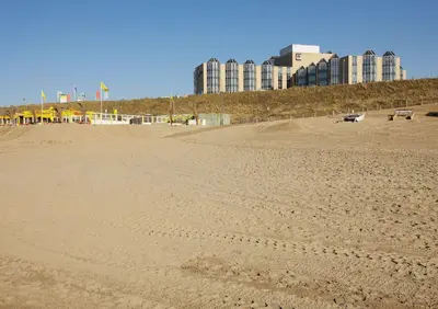 a sandy beach with buildings in the background at NH Zandvoort Hotel in Zandvoort