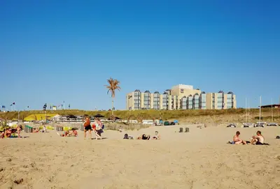 a group of people on a beach with buildings in the background at NH Zandvoort Hotel in Zandvoort