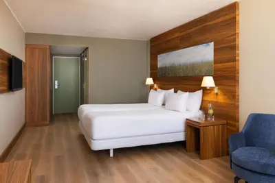 a hotel room with a bed and a blue chair at NH Zandvoort Hotel in Zandvoort