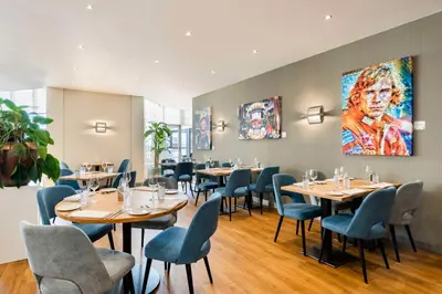 a restaurant with tables and chairs and a painting on the wall at NH Zandvoort Hotel in Zandvoort