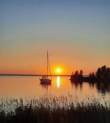 a sailboat sitting on the water at sunset at Studio Flevo Batavia in Lelystad