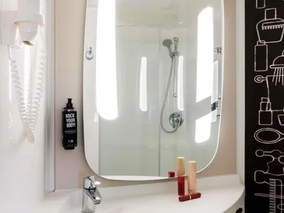 a bathroom with a sink with a shower and a mirror at ibis Amsterdam Centre Stopera in Amsterdam