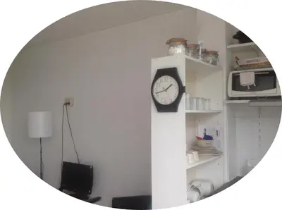 a clock on a column in a room with a mirror at B&B 2 Hoog Lelystad in Lelystad