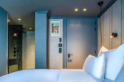 a bedroom with a bed with white pillows and a shower at The Highlander Amsterdam in Amsterdam