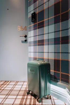 a green suitcase sitting on the floor in a room at The Highlander Amsterdam in Amsterdam