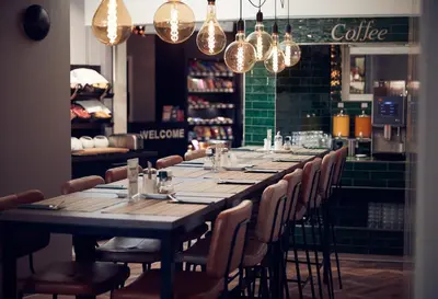 a long table in a restaurant with chairs and lights at Singel Hotel Amsterdam in Amsterdam