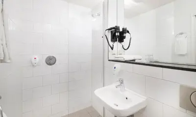a white bathroom with a sink and a phone on the wall at Singel Hotel Amsterdam in Amsterdam