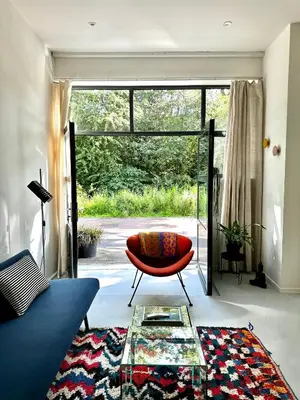 a living room with a red chair and a glass table at Studio in creative district, FREE parking in Amsterdam