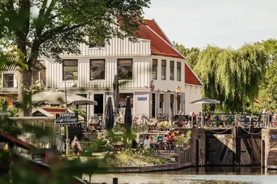 a building next to a river with people sitting outside at Studio in creative district, FREE parking in Amsterdam