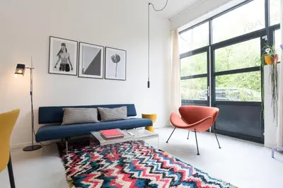 a living room with a blue couch and a rug at Studio in creative district, FREE parking in Amsterdam