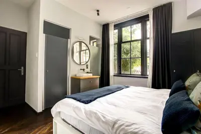 a bedroom with a bed and a sink and a mirror at Canal House with Garden in Amsterdam