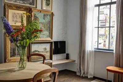 a living room with a table and a vase of flowers at Canal House with Garden in Amsterdam
