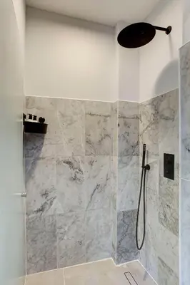 a bathroom with a shower with marble tiles at Canal House with Garden in Amsterdam