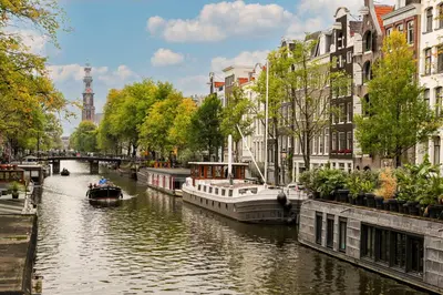 a river with boats in a city with buildings at Canal House with Garden in Amsterdam