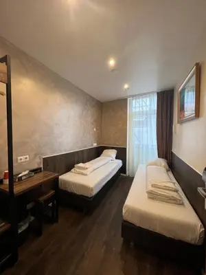 a hotel room with two beds and a mirror at Orange Tulip Hotel in Amsterdam
