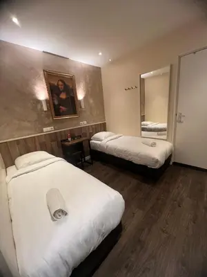 a hotel room with two beds and a mirror at Orange Tulip Hotel in Amsterdam
