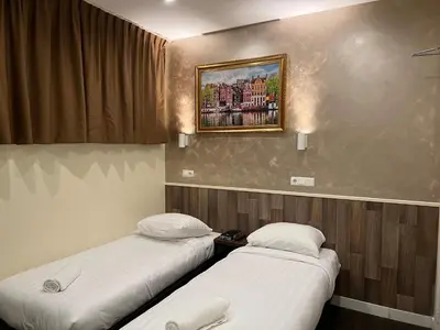 two beds in a room with a picture on the wall at Orange Tulip Hotel in Amsterdam