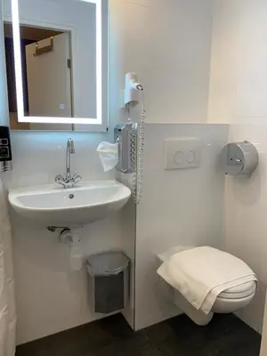 a bathroom with a sink and a toilet and a mirror at Orange Tulip Hotel in Amsterdam