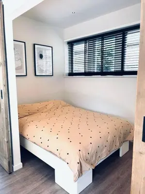 a bedroom with a bed with a comforter and two windows at The Bank's Lodge by ZILT in Limmen