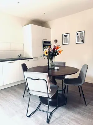 a dining room table with chairs and a vase of flowers at The Bank's Lodge by ZILT in Limmen
