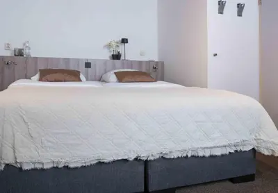 a bedroom with a large bed with a white comforter at Hampshire Hotel Petit Nord in Hoorn