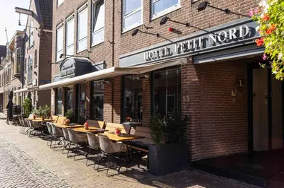 a row of tables outside of a brick building at Hampshire Hotel Petit Nord in Hoorn