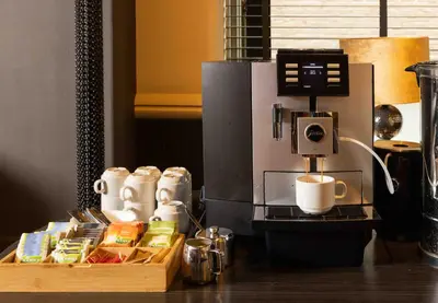 a coffee making machine with cups and food on a table at Hampshire Hotel Petit Nord in Hoorn