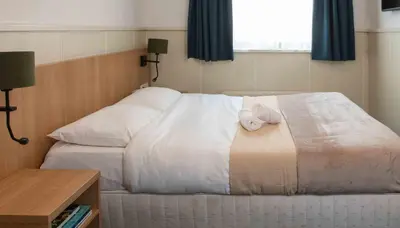 a bedroom with a bed with two towels on it at Hampshire Hotel Petit Nord in Hoorn
